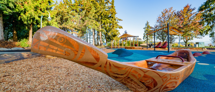 Accessible and cultural playground Canoe with cultural design and accessible swings in the background