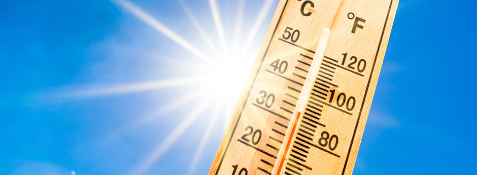 A thermometer at 32 degrees against blue sky background with a radiant sun