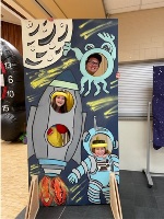 Youth leaders posing behind an outer space mural.